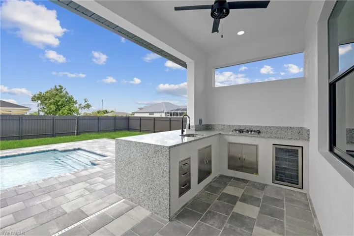 View of patio / terrace with sink, ceiling fan, a fenced in pool, and area for grilling