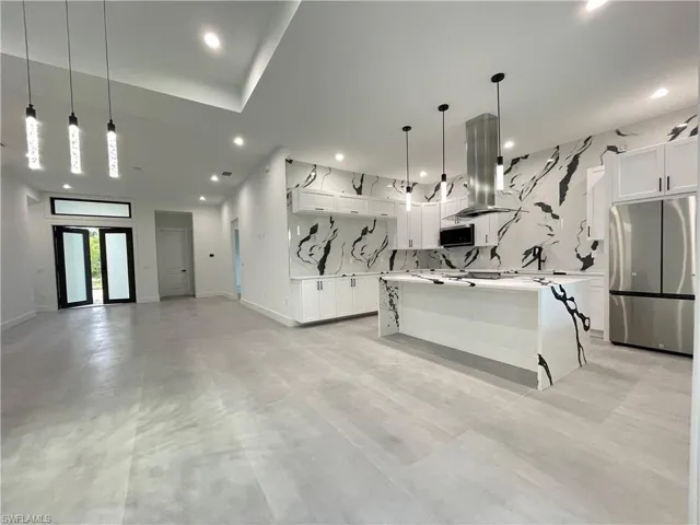 Kitchen with a center island, backsplash, appliances with stainless steel finishes, and white cabinetry