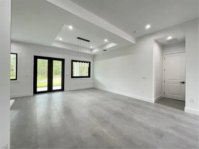 Empty room with a tray ceiling, french doors, and plenty of natural light