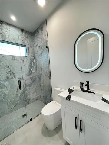 Bathroom featuring vanity, toilet, and a shower with door