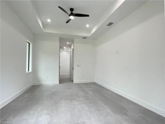 Empty room with ceiling fan and a tray ceiling