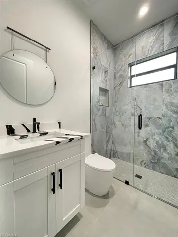 Bathroom featuring vanity, toilet, tile patterned floors, and walk in shower