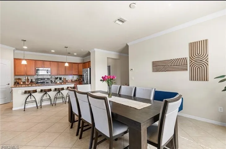 Dining space featuring ornamental molding and light tile patterned floors