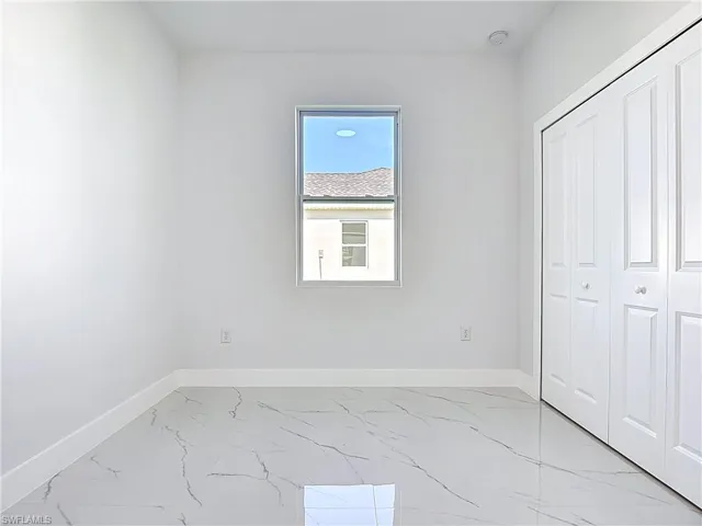 Unfurnished bedroom featuring light marble finish floors and a closet