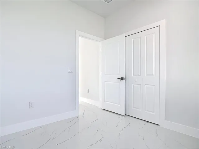 Unfurnished bedroom featuring light marble finish floors and a closet