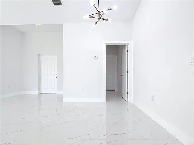 Unfurnished room with light marble finish flooring and a chandelier