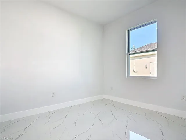 Spare room featuring baseboards and marble finish flooring