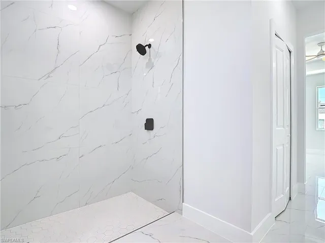 Bathroom with a marble finish shower and baseboards