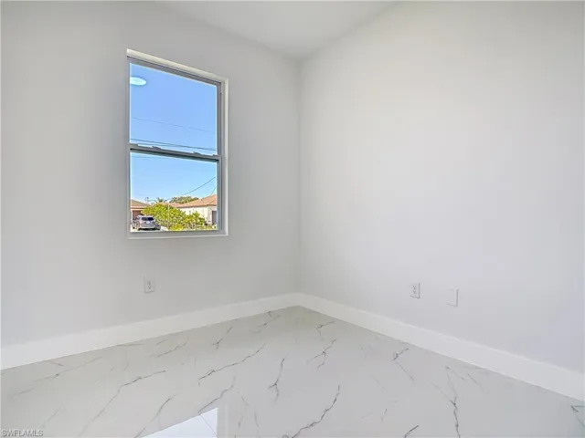 Empty room with baseboards and marble look tiles