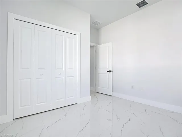 Unfurnished bedroom featuring light marble finish flooring and a closet