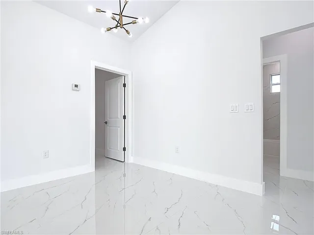 Unfurnished room featuring a chandelier and light marble finish floors