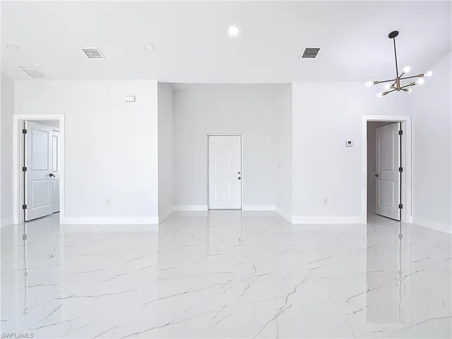 Spare room featuring light marble finish floors, a chandelier, and recessed lighting