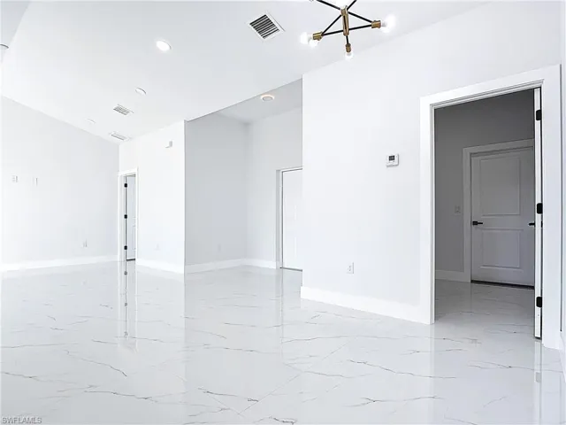 Spare room featuring a chandelier, light marble finish floors, and recessed lighting