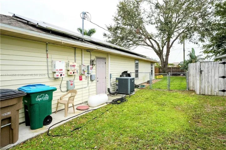 Rear view of property featuring a gate and roof mounted solar panels