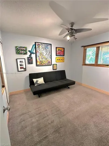 Living area featuring light colored carpet, a textured ceiling, and ceiling fan