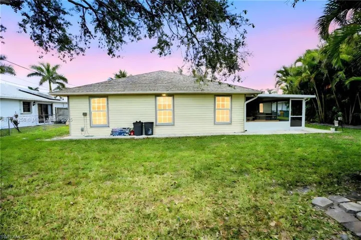 Rear view of house featuring a patio area, a yard, and a sunroom