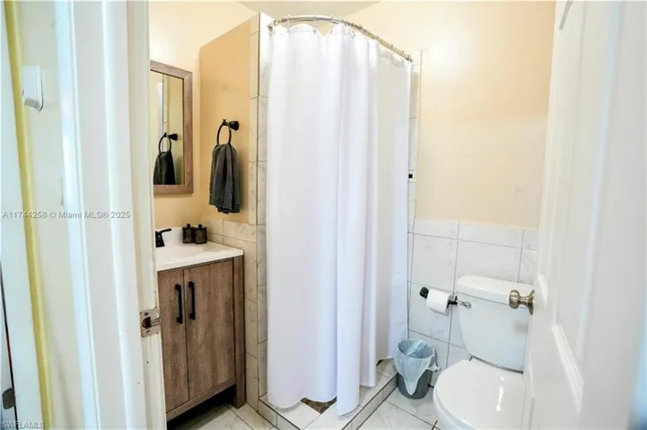Full bath featuring tile walls, vanity, and a stall shower