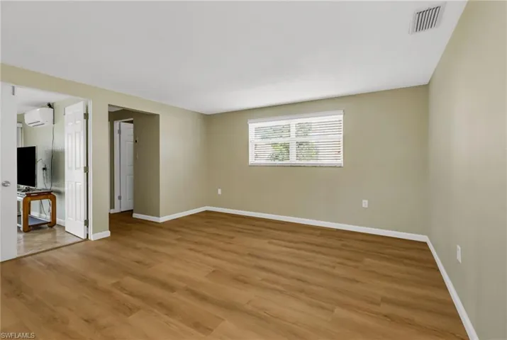 Unfurnished living room featuring light wood finished floors and a wall mounted air conditioner