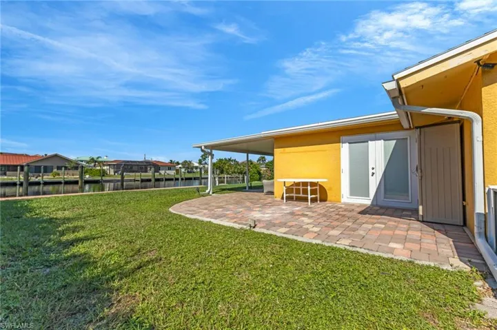 View of grassy yard featuring a water view and a patio