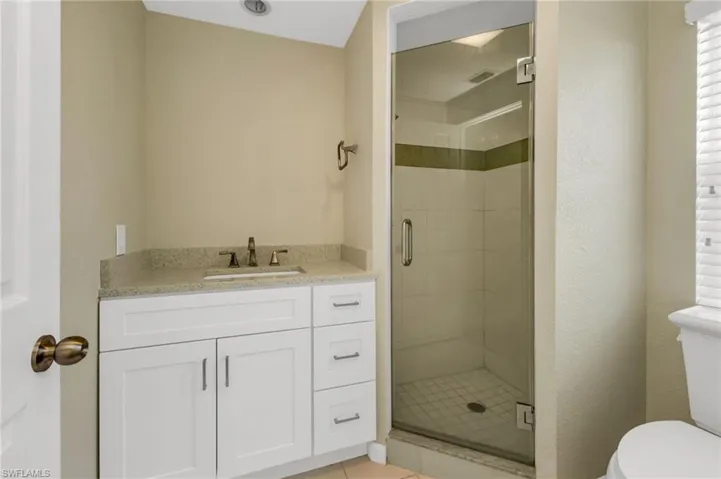 Bathroom featuring vanity, light tile patterned floors, and a stall shower