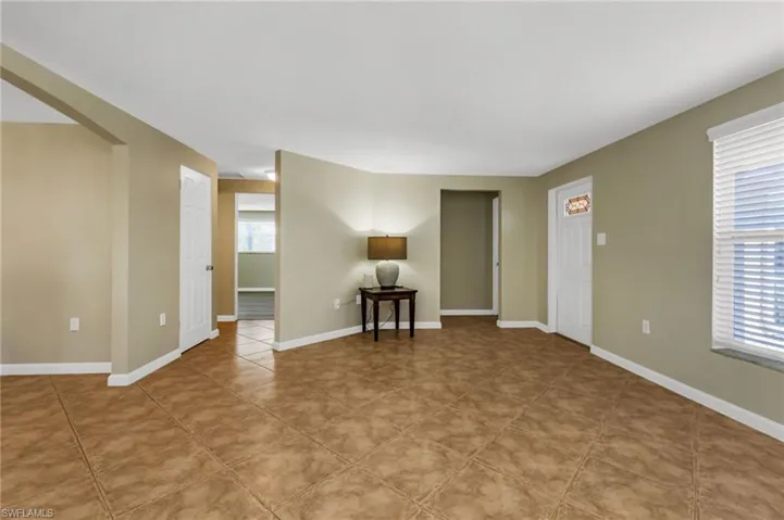 Unfurnished living room featuring arched walkways and light tile patterned floors