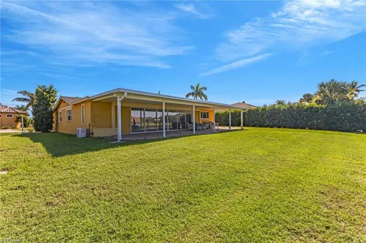 Rear view of house with a yard, stucco siding, and a patio