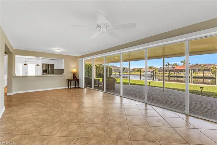 Unfurnished room featuring a water view, a residential view, light tile patterned floors, and ceiling fan