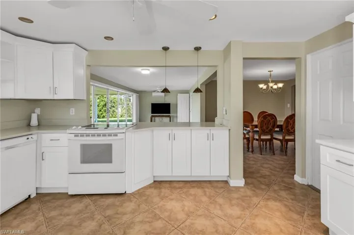 Kitchen featuring white appliances, decorative light fixtures, white cabinets, a ceiling fan, and a chandelier