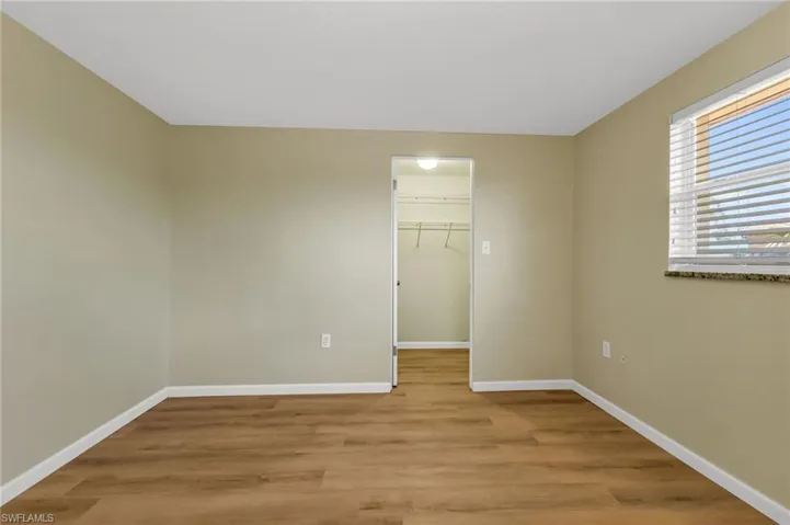 Unfurnished bedroom featuring a walk in closet and light wood-type flooring