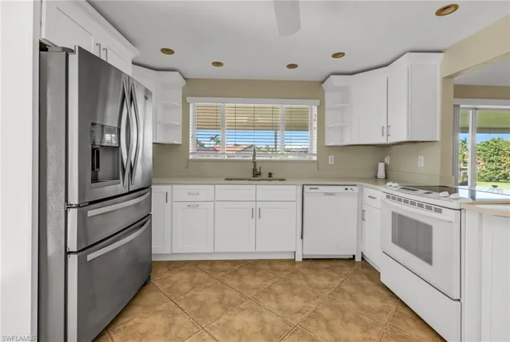 Kitchen with open shelves, white appliances, white cabinets, and recessed lighting