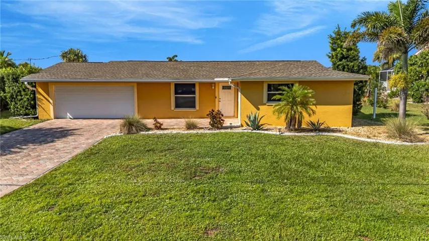Ranch-style house featuring a garage, stucco siding, decorative driveway, and a front lawn