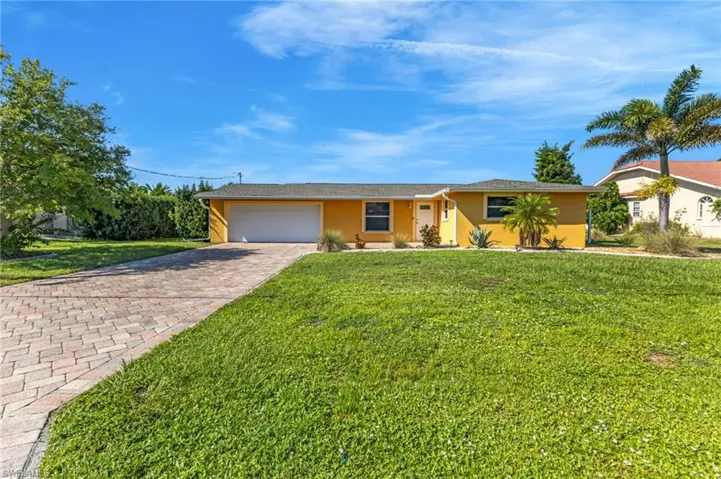Ranch-style home featuring a garage, stucco siding, decorative driveway, and a front yard