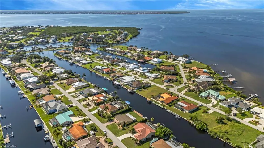 Aerial view of property and surrounding area featuring a nearby body of water and nearby suburban area