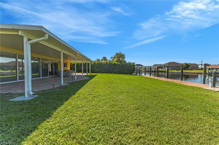 View of grassy yard with a water view, a patio, and a residential view