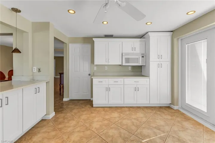 Kitchen featuring white cabinets, recessed lighting, decorative light fixtures, and white microwave
