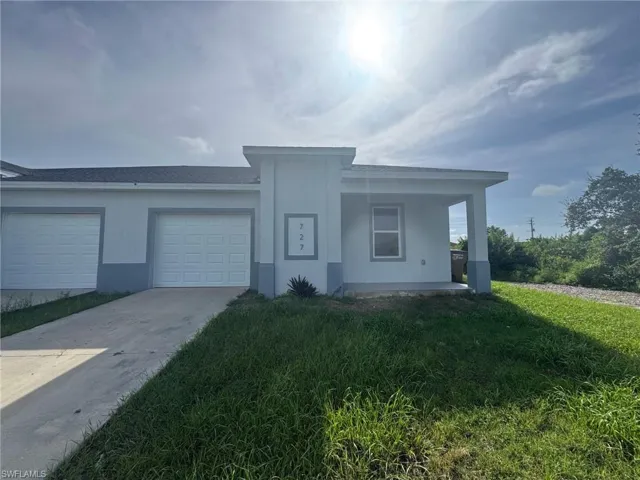 View of front of home featuring driveway, an attached garage, and stucco siding
