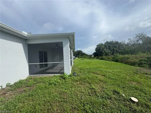 View of grassy yard featuring a sunroom