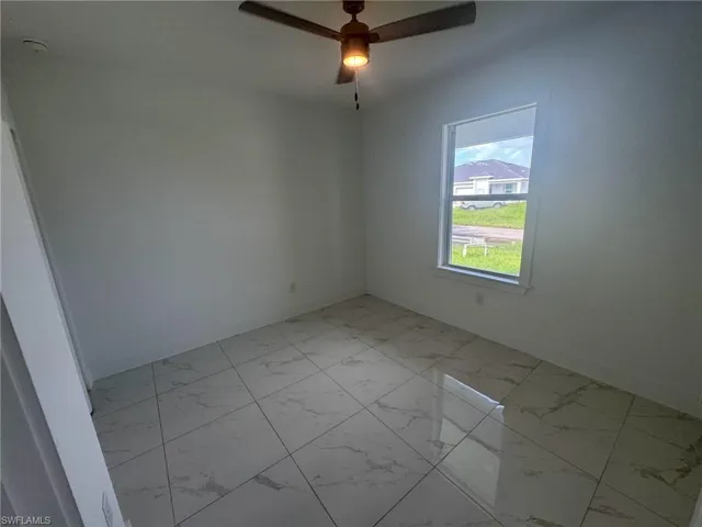 Spare room featuring light marble finish floors and a ceiling fan