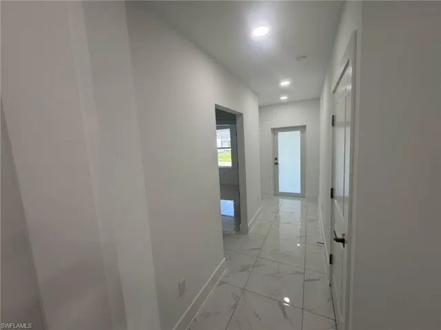 Hallway featuring light marble finish floors and recessed lighting