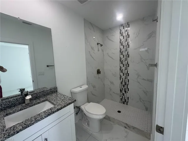 Full bathroom featuring a marble finish shower, vanity, and light marble finish floors