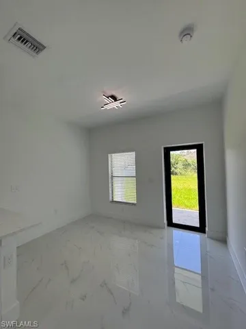 Unfurnished room with light marble finish flooring and baseboards, rear exit door.