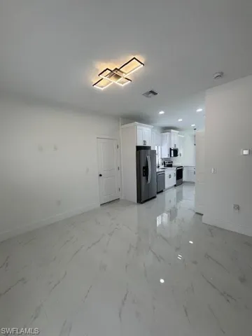Unfurnished living room featuring light marble finish flooring and recessed lighting