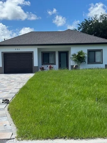 Single story home with stucco siding, an attached garage, a front lawn, and a shingled roof
