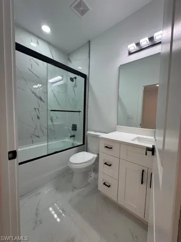 Guest Full bathroom featuring bath / shower combo with glass door, vanity, and light marble finish floors