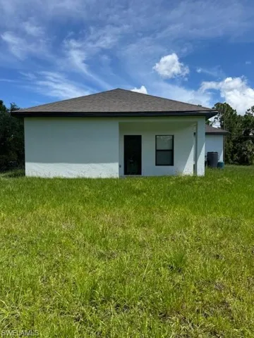 Rear view of property with stucco siding and a lawn