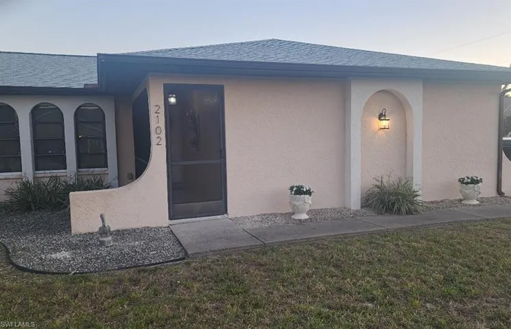 Cream stucco exterior with a dark grey shingle roof