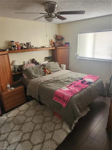 Bedroom featuring wood-finish flooring, a window with blinds, and a ceiling fan with integrated lighting