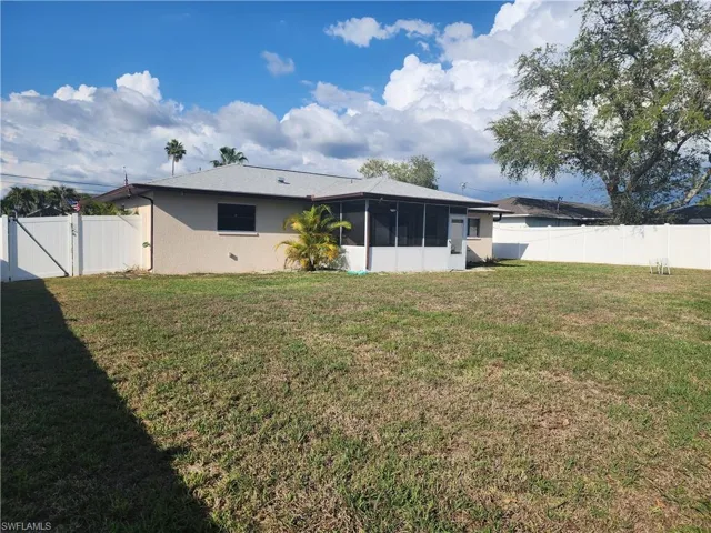 Expansive backyard featuring a screened-in patio, mature landscaping, and a privacy fence
