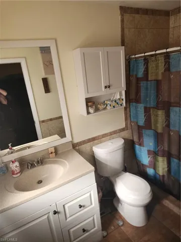 Bathroom featuring a single vanity with built-in sink, white cabinetry with dark hardware, a framed mirror, and a white wall-mounted storage cabinet