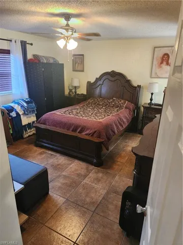 Bedroom featuring tile flooring, a ceiling fan with integrated lighting, and window blinds